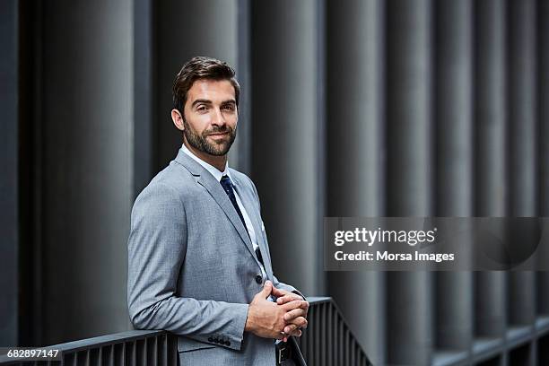 confident businessman with hands clasped outdoors - goed gekleed stockfoto's en -beelden