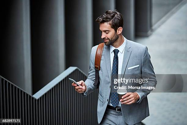 businessman with cup and mobile phone on stairs - homem bonito imagens e fotografias de stock