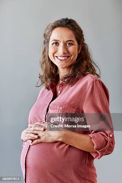 pregnant businesswoman with hands on stomach - embarazada fotos fotografías e imágenes de stock