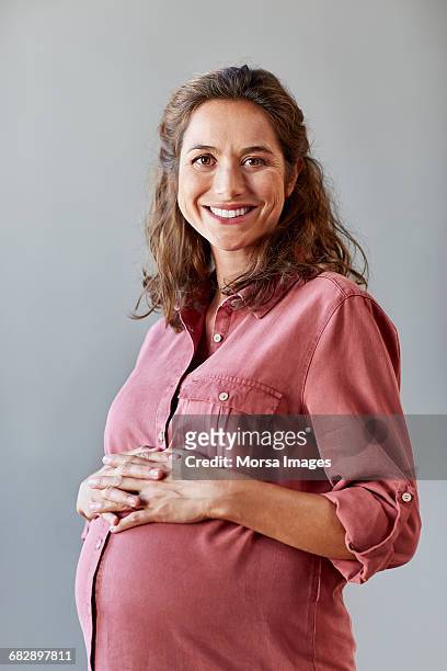 pregnant businesswoman with hands on stomach - pink blouse foto e immagini stock