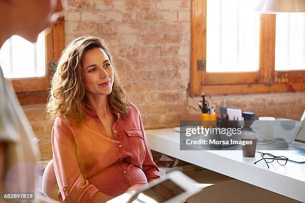 pregnant businesswoman looking away at desk - business woman blouse stock-fotos und bilder