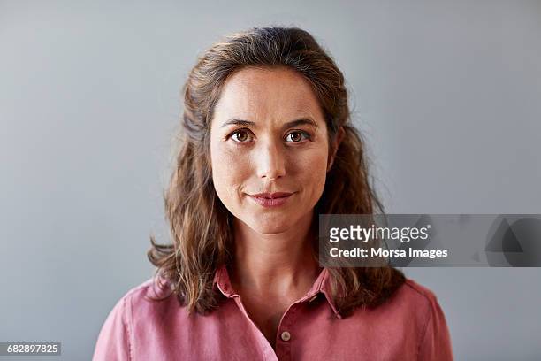 confident businesswoman over gray background - mid adult stock-fotos und bilder