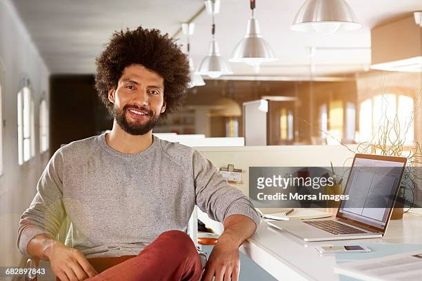 confident businessman sitting at desk - low key beleuchtung stock-fotos und bilder