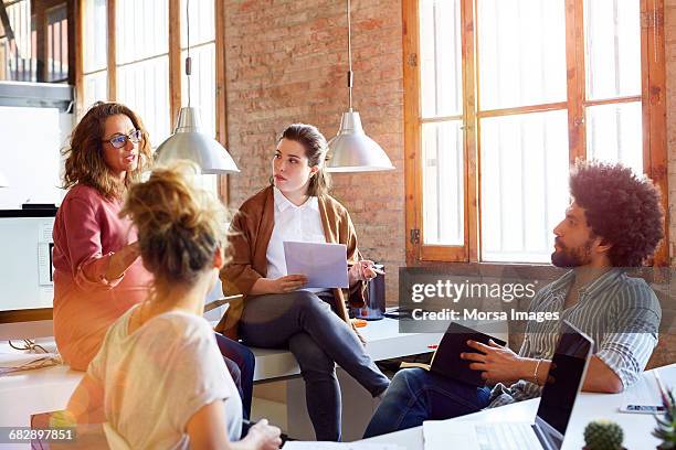 pregnant businesswoman discussing with colleagues - leanincollection stockfoto's en -beelden