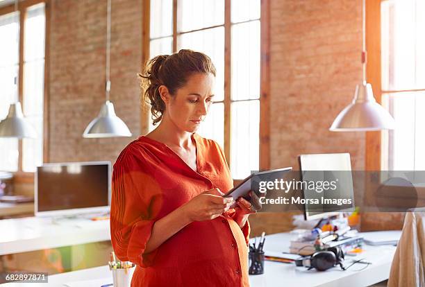 pregnant businesswoman using tablet pc in office - red blouse fotografías e imágenes de stock