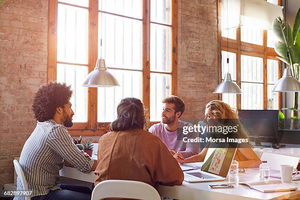 professionals sitting at desk in office - four people talking stock pictures, royalty-free photos & images