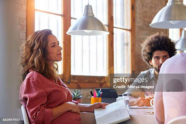 pregnant businesswoman with colleagues in office - antenatal stockfoto's en -beelden