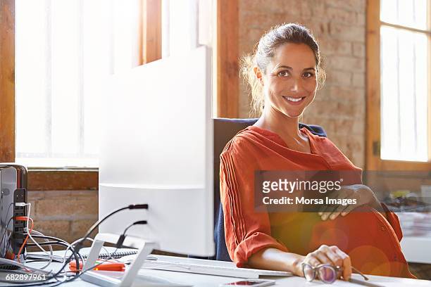 pregnant businesswoman sitting at computer desk - blouse man stockfoto's en -beelden