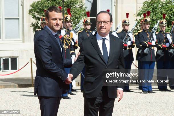 French outgoing President Francois Hollande shakes hands with his successor Emmanuel Macron as he leaves the Elysee presidential Palace after the...