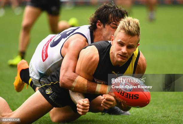 Brandon Ellis of the Tigers handballs whilst being tackled by Brady Grey of the Dockers during the round eight AFL match between the Richmond Tigers...