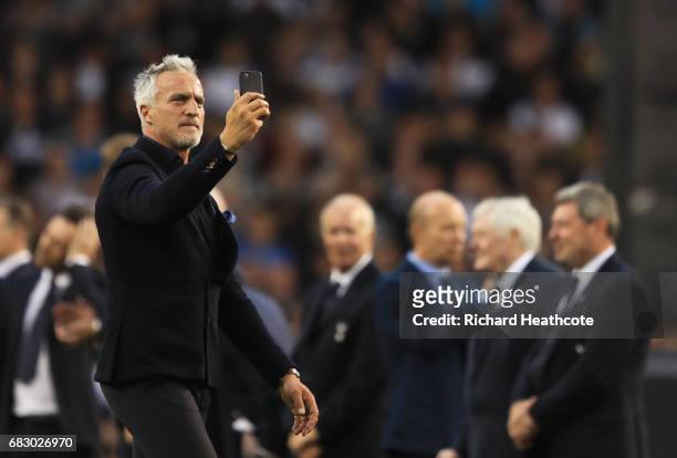 David Ginola films with with his phone as he walks onto the pitch during the closing ceremony after the Premier League match between Tottenham...