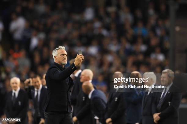 David Ginola films with with his phone as he walks onto the pitch during the closing ceremony after the Premier League match between Tottenham...