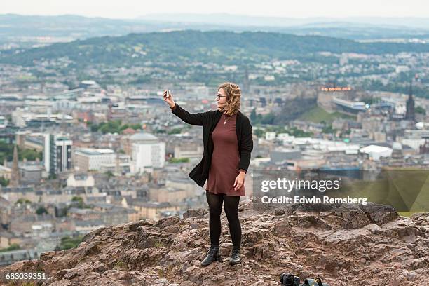 young girl taking a photo of herself - arthurs seat stock-fotos und bilder