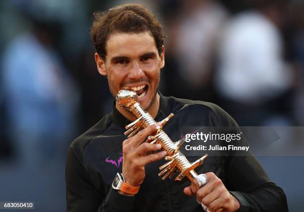 Rafael Nadal of Spain bites the winners trophy after his win over Dominic Thiem of Austria in the final during day nine of the Mutua Madrid Open...