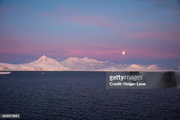 moonrise over snow-covered mountains at dusk - antarctica sunset stock pictures, royalty-free photos & images