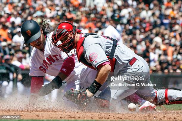 Brandon Crawford of the San Francisco Giants scores a run ahead of a tag from Devin Mesoraco of the Cincinnati Reds during the first inning at AT&T...
