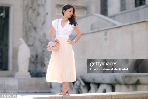 May Berthelot, fashion blogger and Head of Legal at Videdressing.com, wears an Asos white ruffled top, an Asos pleated pink skirt, Louboutin Pigalle...