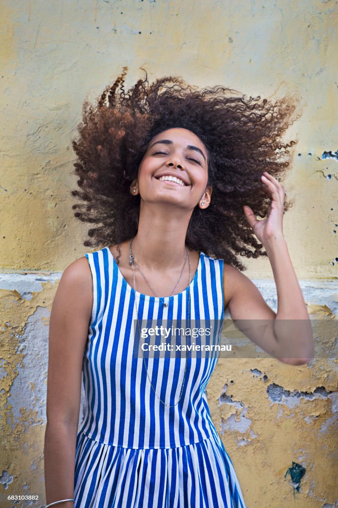 Young woman tossing hair against weathered wall