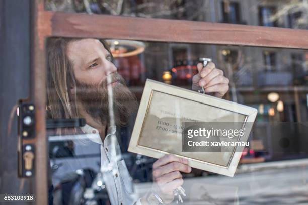 owner with open sign at furniture store window - open sign stock pictures, royalty-free photos & images
