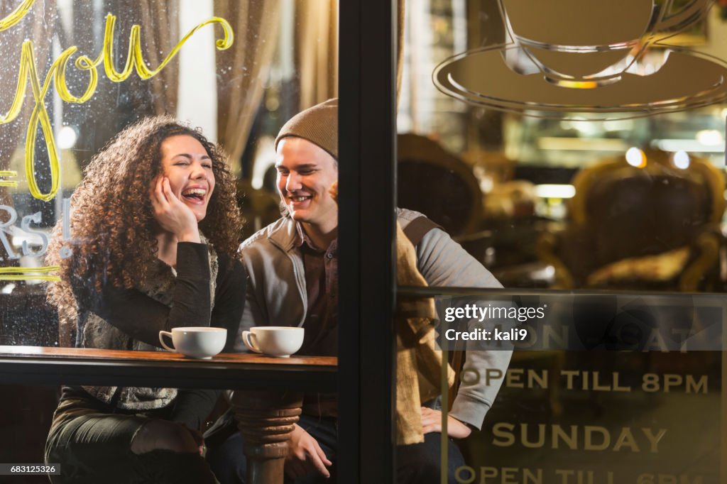 Young couple sitting in coffee shop talking, laughing