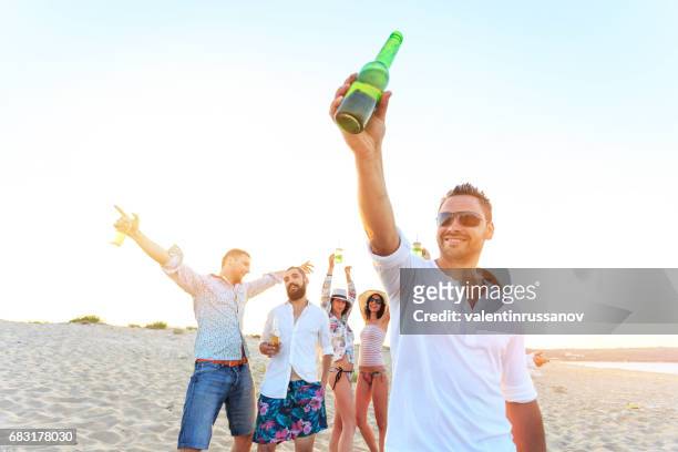 young people cheering on beach - comemoração conceito imagens e fotografias de stock