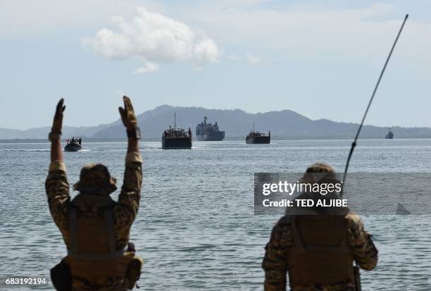 Members of Philippine navy special operations group signal to Philippine landing ships loaded with Philippine-US marines, and civilian volunteers as...