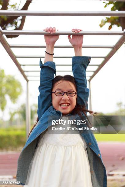 cute girl playing horizontal bar at the elementary schoolyard. - girl rising stock pictures, royalty-free photos & images