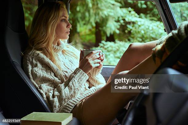 young woman relaxing drinking tea in car - knitted car stock pictures, royalty-free photos & images