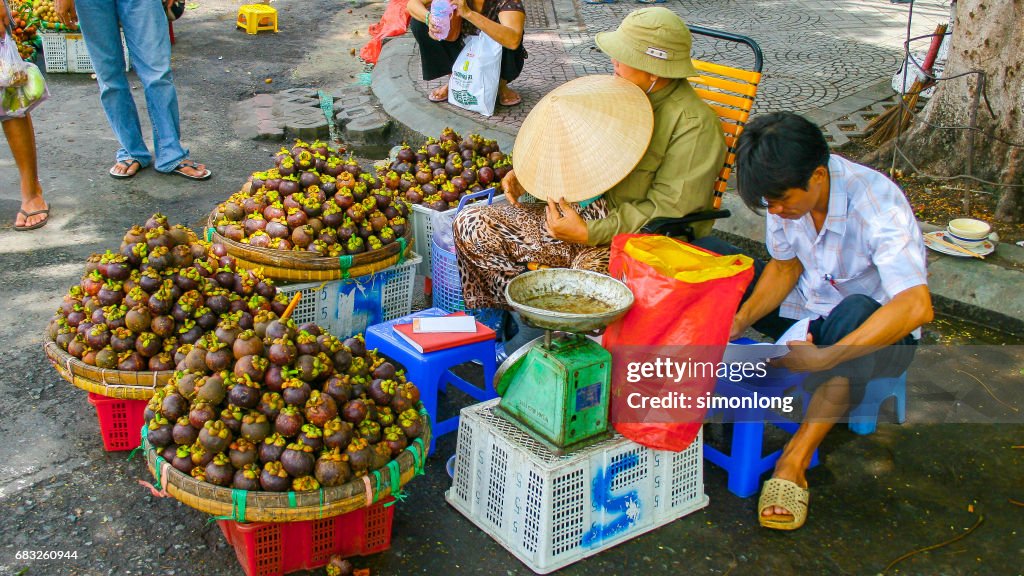 Two people are selling mangosteen