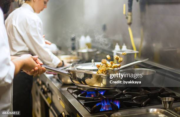 chef preparing cuisine in hotel kitchen - chef vs chef stock pictures, royalty-free photos & images