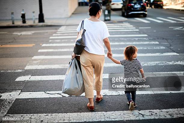 mother and son crossing street. - überqueren stock-fotos und bilder
