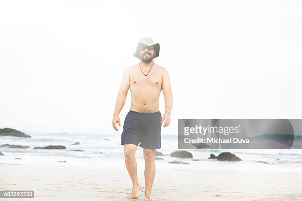 man walking next to beach in swimsuit - one piece stock pictures, royalty-free photos & images