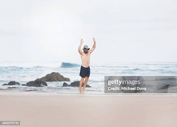 man jumping playing on beach and next to ocean - playa tamarindo - fotografias e filmes do acervo