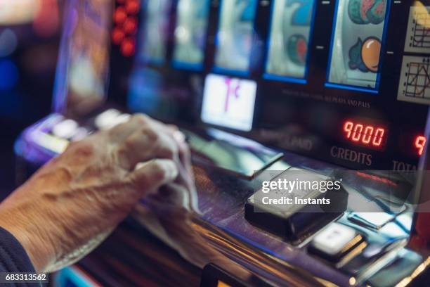 a mature/senior woman, sitting in front of a slot machine, is gambling in a las vegas casino. - fruit machine stock pictures, royalty-free photos & images