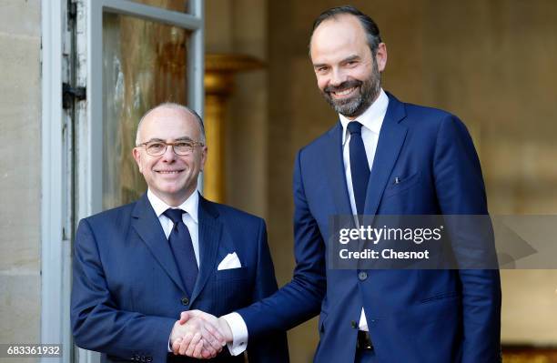 France's newly-appointed Prime Minister Edouard Philippe and outgoing Prime Minister Bernard Cazeneuve shake hands during the official handover...