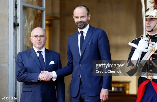 France's newly-appointed Prime Minister Edouard Philippe and outgoing Prime Minister Bernard Cazeneuve shake hands during the official handover...