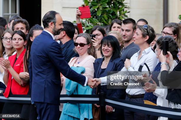 France's newly-appointed Prime Minister Edouard Philippe shake hands with employees after an official handover ceremony with outgoing Prime Minister...