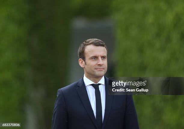 Newly-elected French President Emmanuel Macron and German Chancellor Angela Merkel walk to review a guard of honour upon Macron's arrival at the...