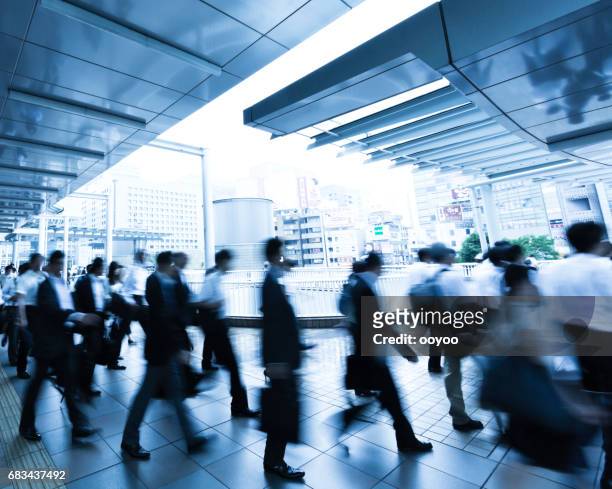 crowds of commuters walking through pedestrian walkway on a rainy morning - japan commuters stock pictures, royalty-free photos & images