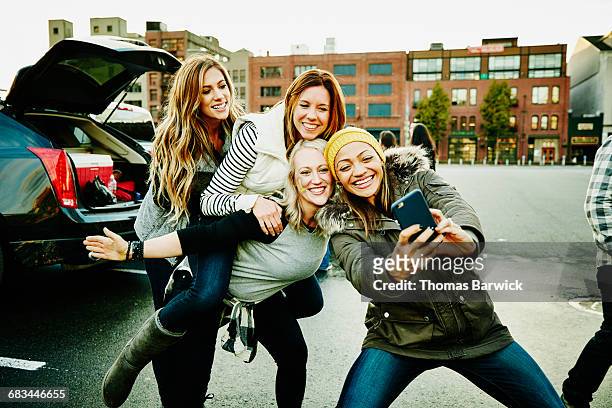 smiling women taking selfie at tailgating party - fan appreciation day stock-fotos und bilder