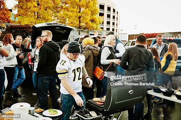 man preparing food for friends at tailgate party - american bbq stock pictures, royalty-free photos & images