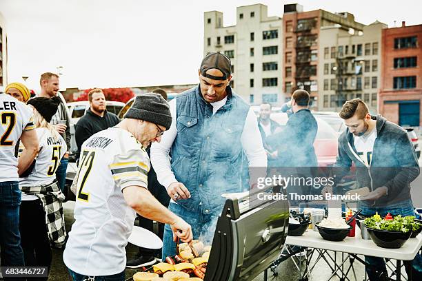 men cooking at barbecue during tailgating party - tailgating stock-fotos und bilder