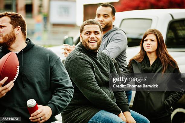 man sitting on truck during tailgating party - football tailgate stock pictures, royalty-free photos & images