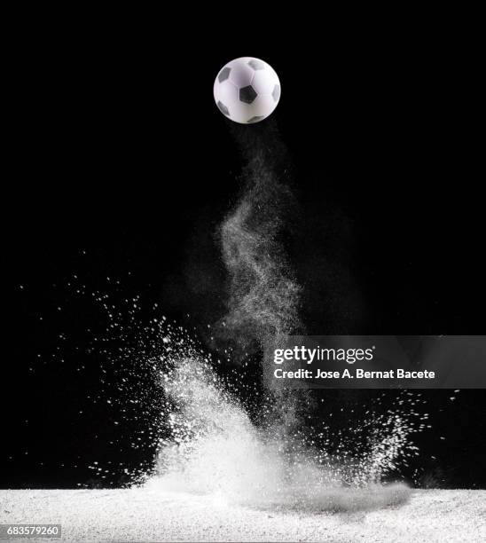 impact and rebound of a ball of football  on a surface of land and powder on a black background - portrait studio shot stock pictures, royalty-free photos & images