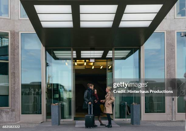 three business colleagues meeting at a hotel - entrance stockfoto's en -beelden