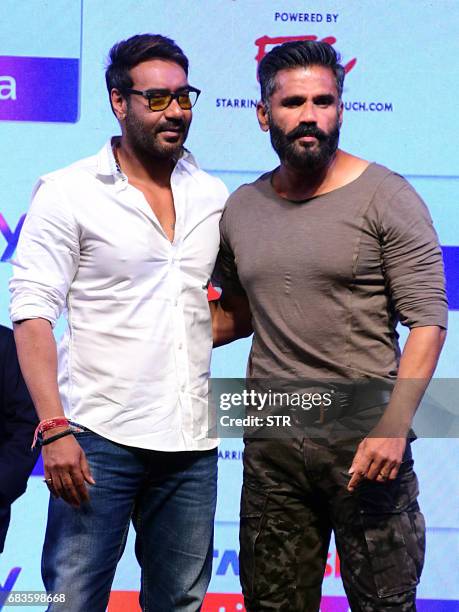 Indian Bollywood actors Ajay Devgn and Suniel Shetty talk onstage during the launch of 'Acting Adda' in Mumbai on 16 May, 2017. / AFP PHOTO / STR