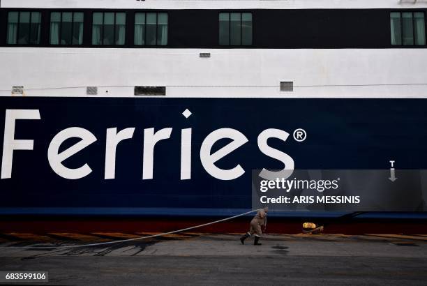 Dock worker walks in front of a docked ferry at the port of Peiraeus during a 48-hour strike by the sailor union on May 16, 2017. Greek unions today...