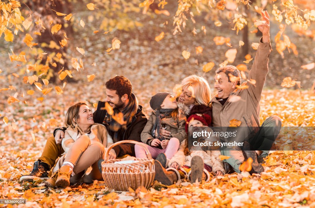 Playful multi-generation family among autumn leaves on a picnic.