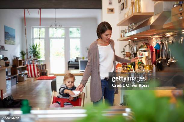 mother with little daughter in kitchen - multitasking stock-fotos und bilder