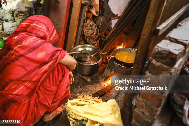Dehli, India A woman is cooking in her living room on a naked flame. Slum of the city district Seemapuri, where the Caritas and the NGO Chentanalaya...